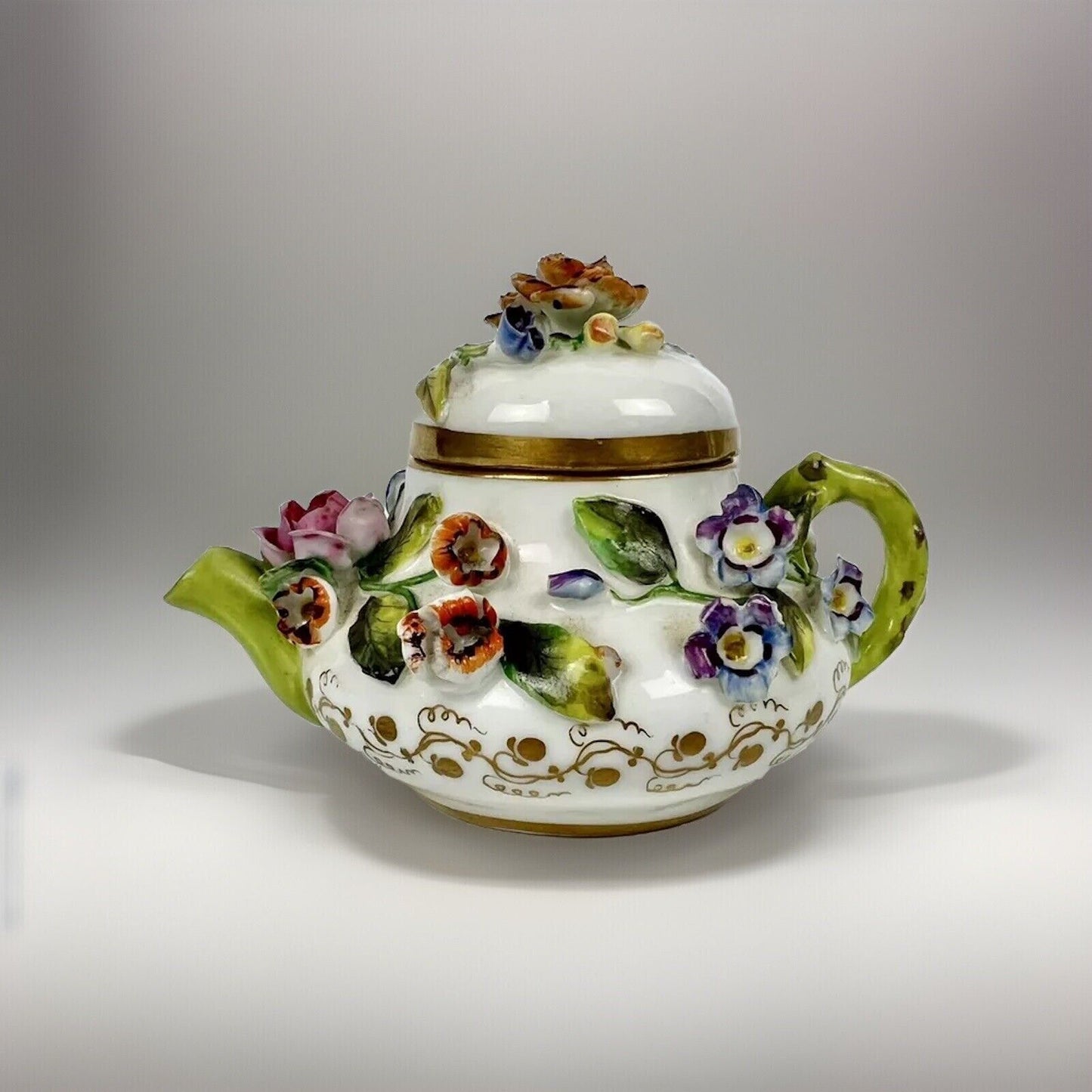 A Rockingham flower-encrusted squat globular teapot and cover. Puce mark 1831-7