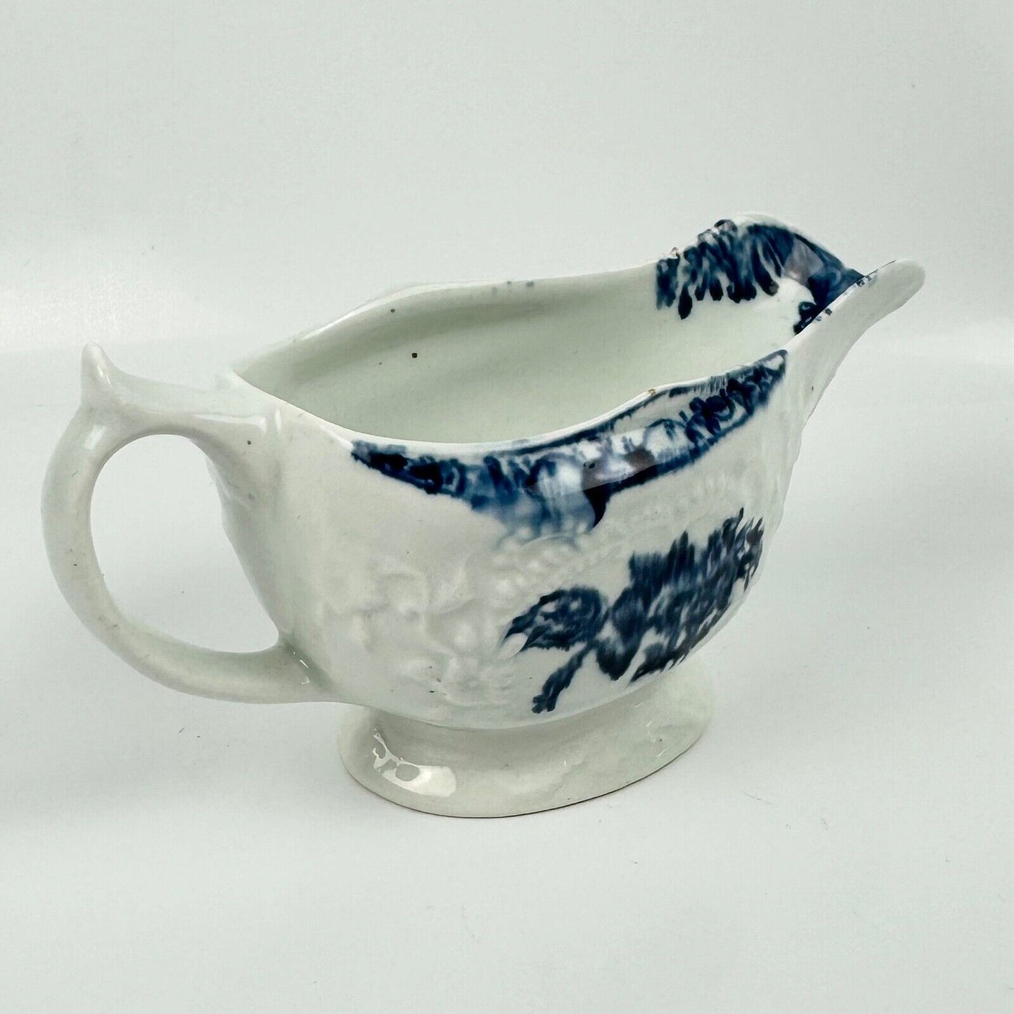 A Lowestoft small sauceboat c1775 with moulded panels and printed decoration.