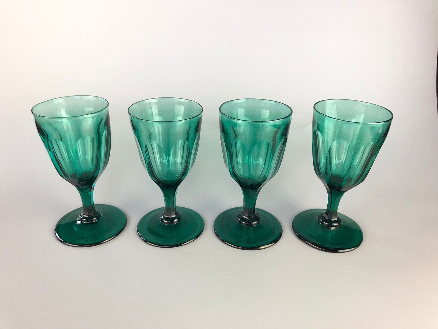 A set of four early Victorian (c1840) green glass slice-cut wine glasses