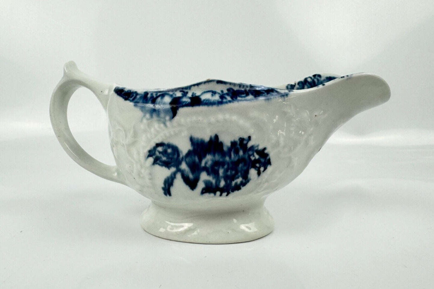 A Lowestoft small sauceboat c1775 with moulded panels and printed decoration.