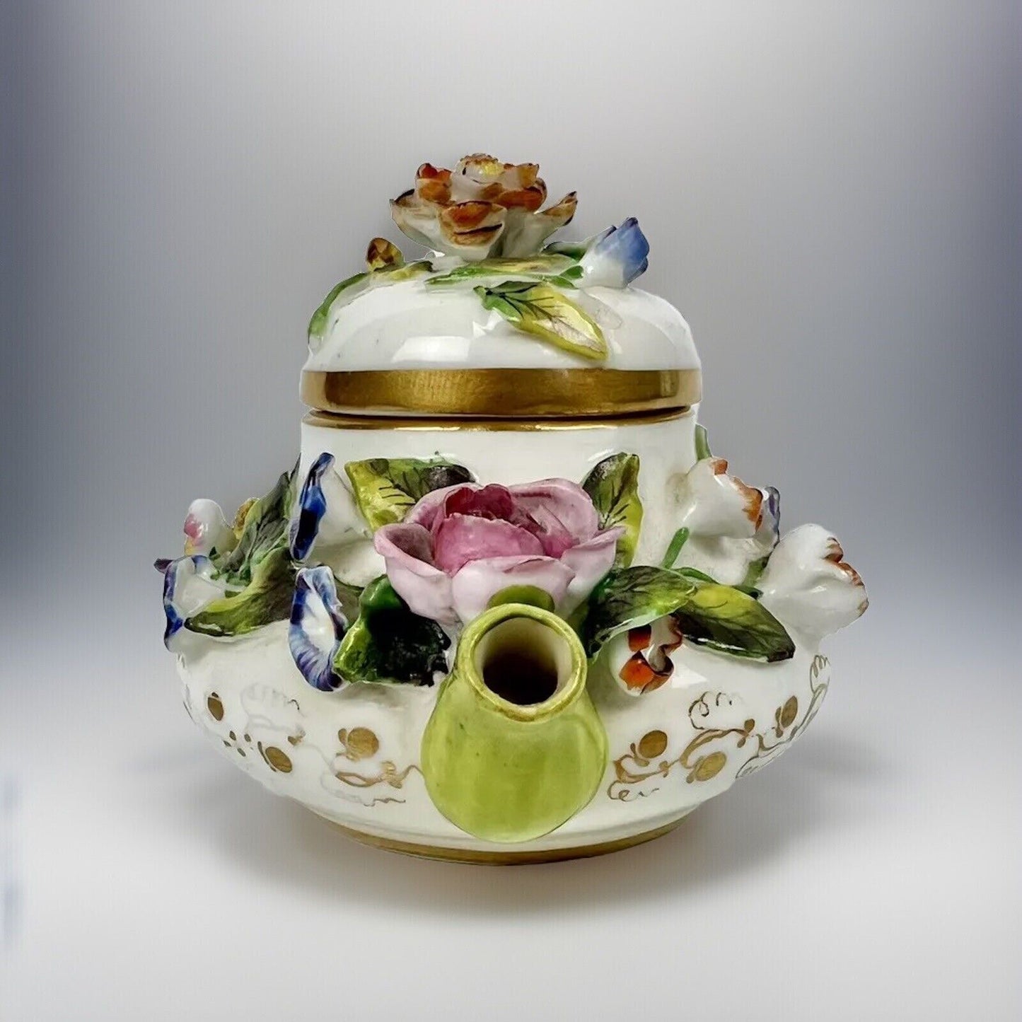 A Rockingham flower-encrusted squat globular teapot and cover. Puce mark 1831-7