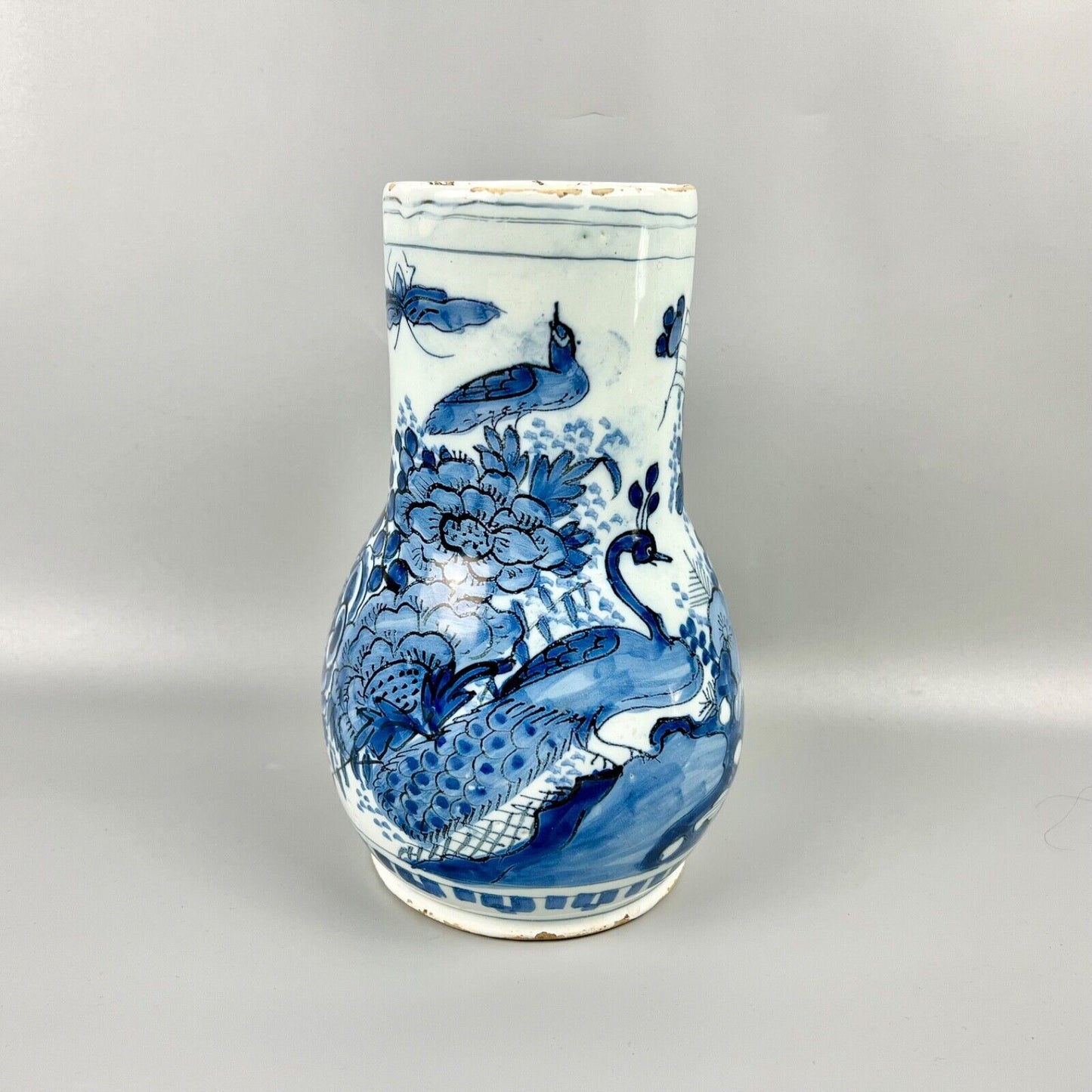 An early 18thc Dutch Delft jug painted with peacocks, holey rocks and peonies