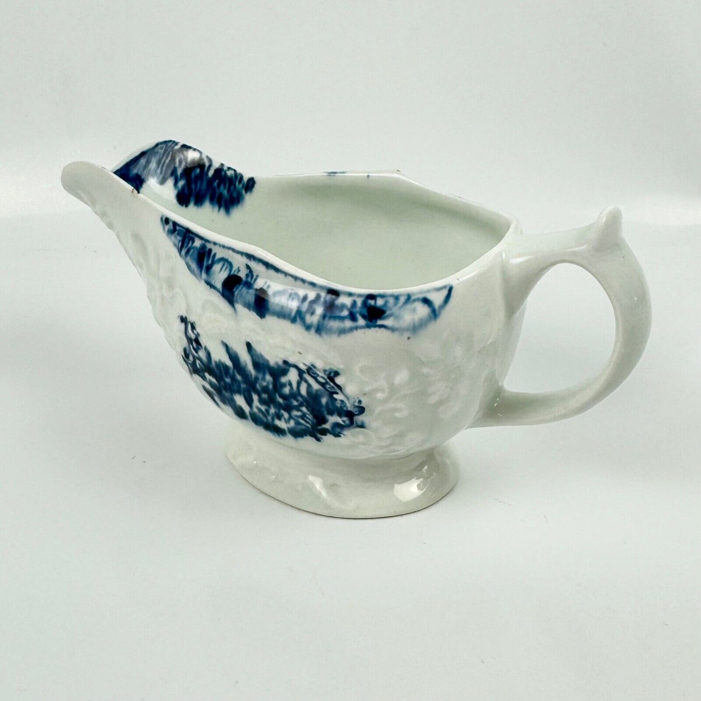 A Lowestoft small sauceboat c1775 with moulded panels and printed decoration.