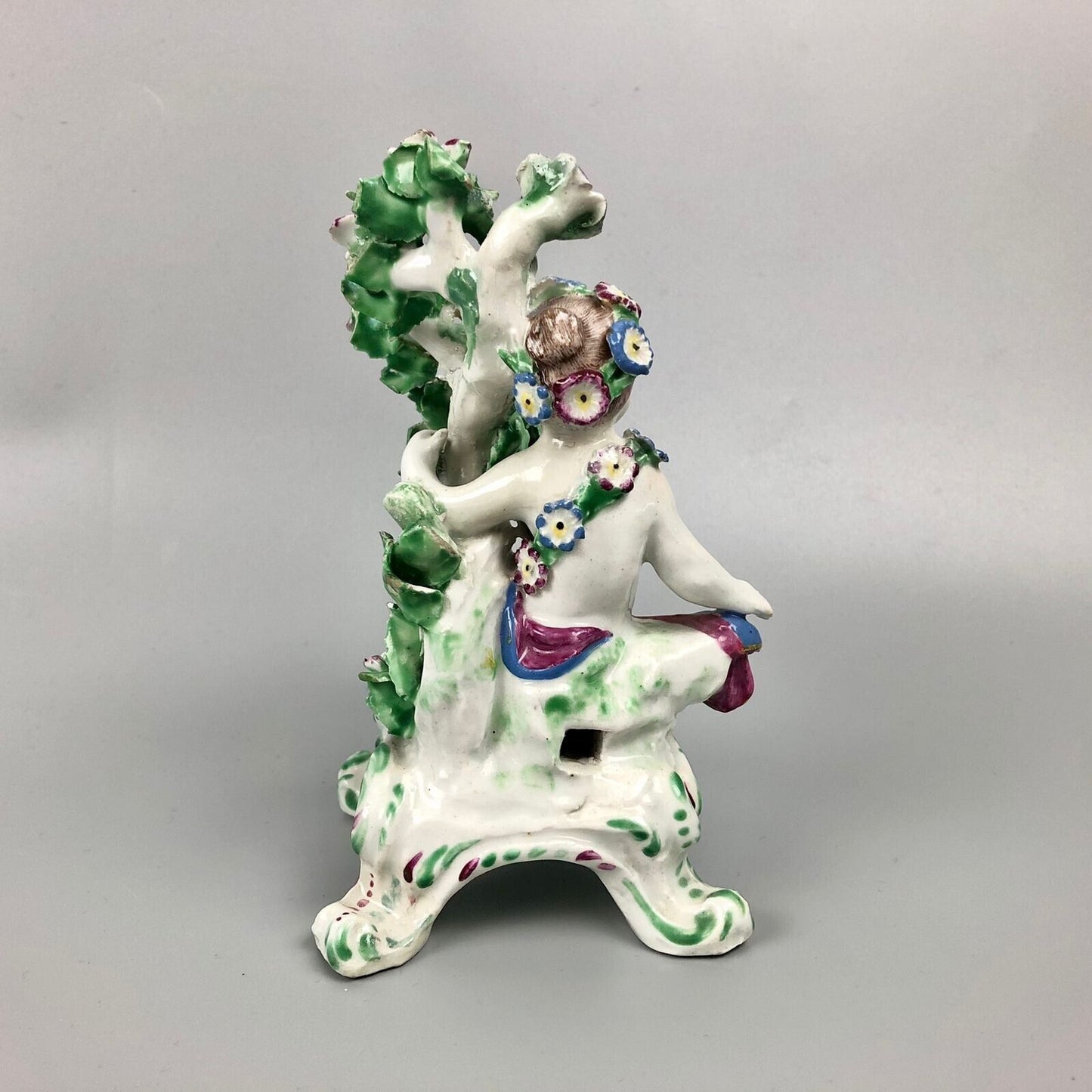 A pair of Bow putti with rococo C-scroll bases and bocage c.1760