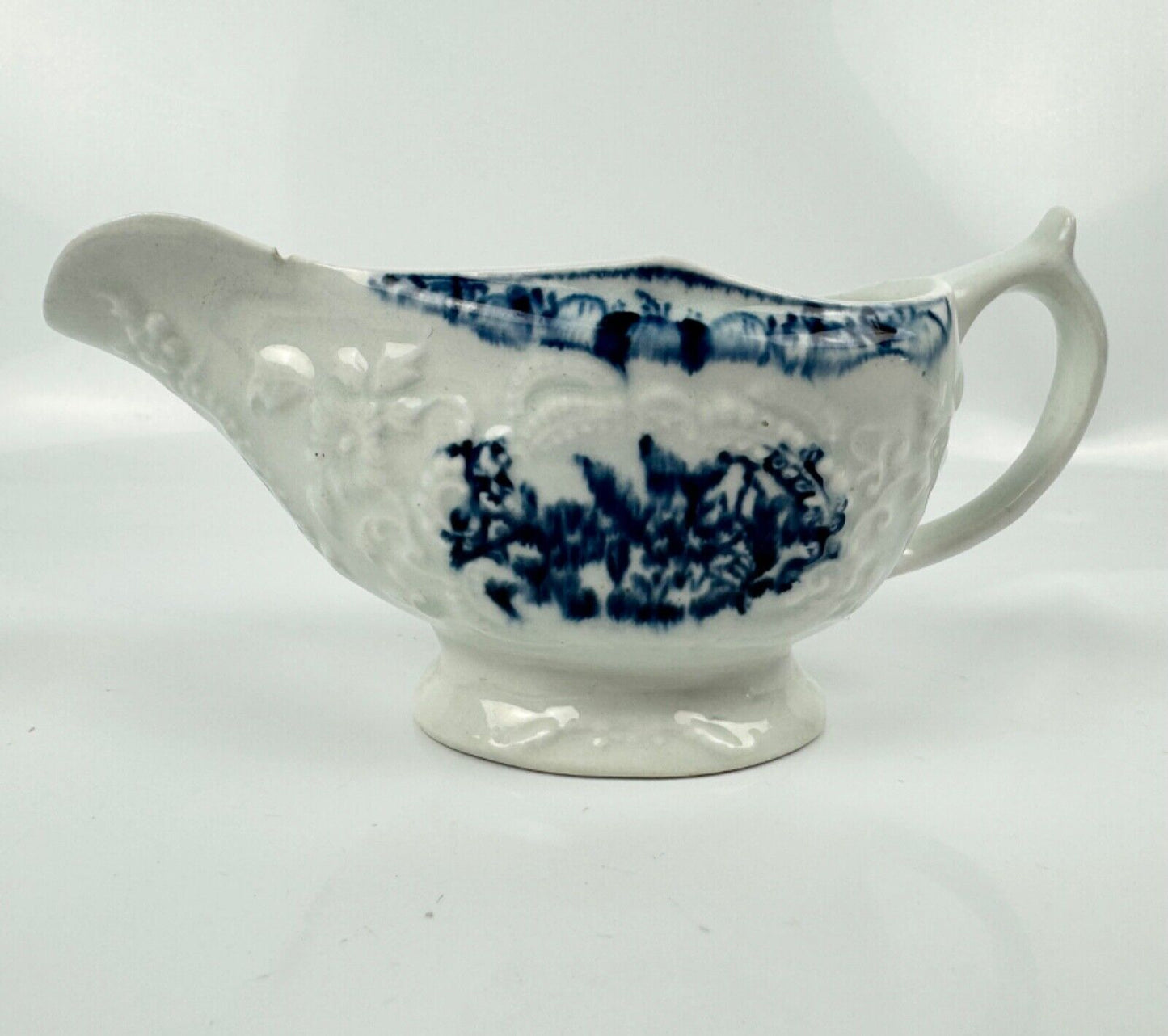 A Lowestoft small sauceboat c1775 with moulded panels and printed decoration.