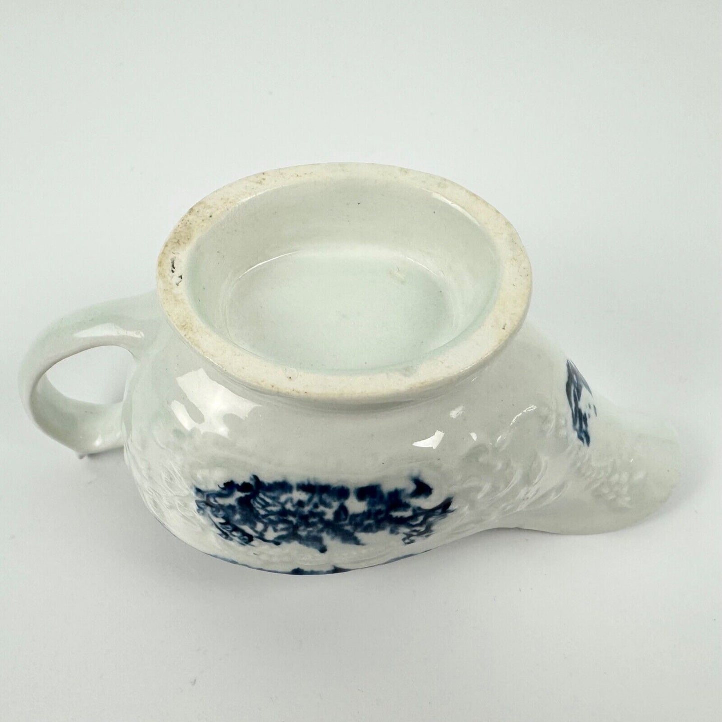 A Lowestoft small sauceboat c1775 with moulded panels and printed decoration.
