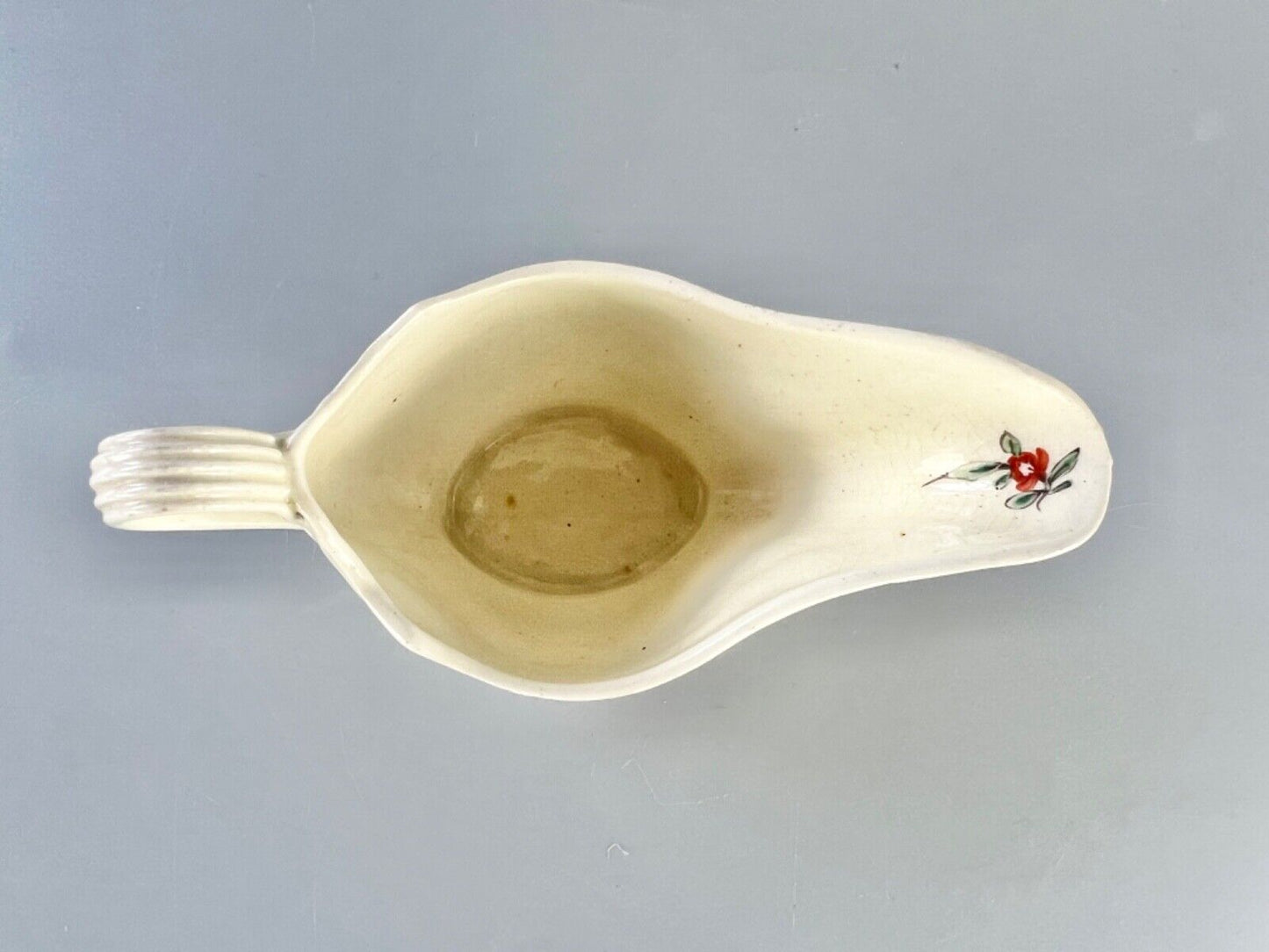 A c1775 creamware sauceboat painted with floral sprays. Probably Staffordshire.