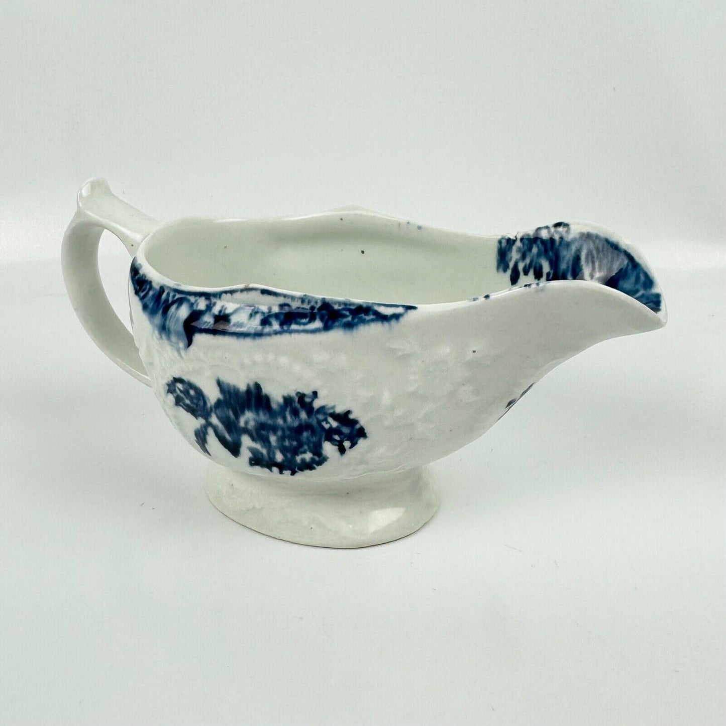A Lowestoft small sauceboat c1775 with moulded panels and printed decoration.