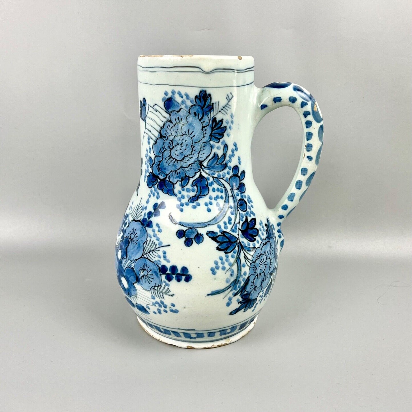 An early 18thc Dutch Delft jug painted with peacocks, holey rocks and peonies