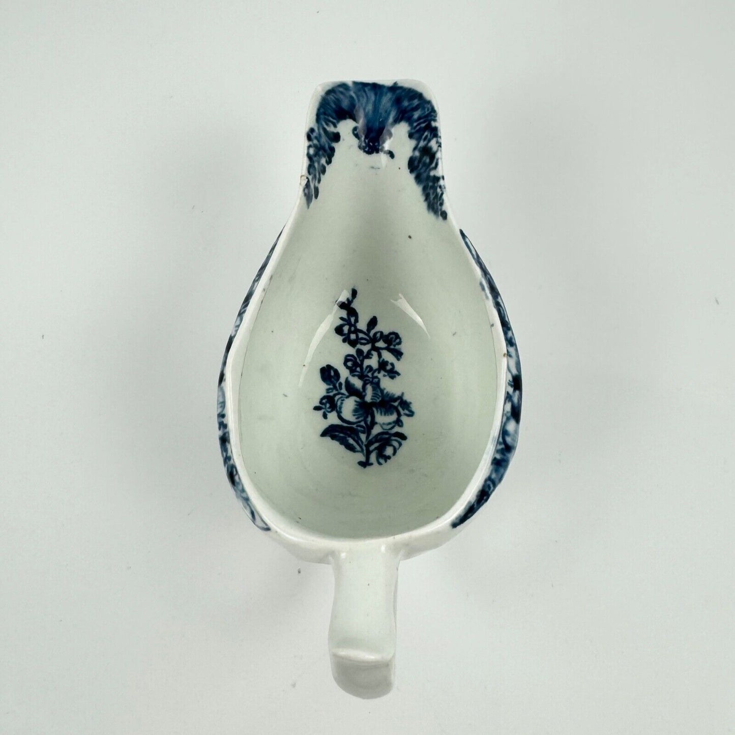 A Lowestoft small sauceboat c1775 with moulded panels and printed decoration.
