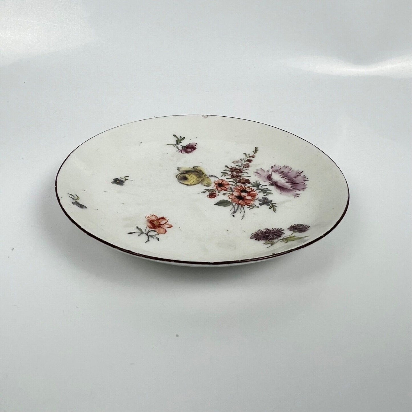A A Chelsea floral-painted saucer with brown rim. c.1758