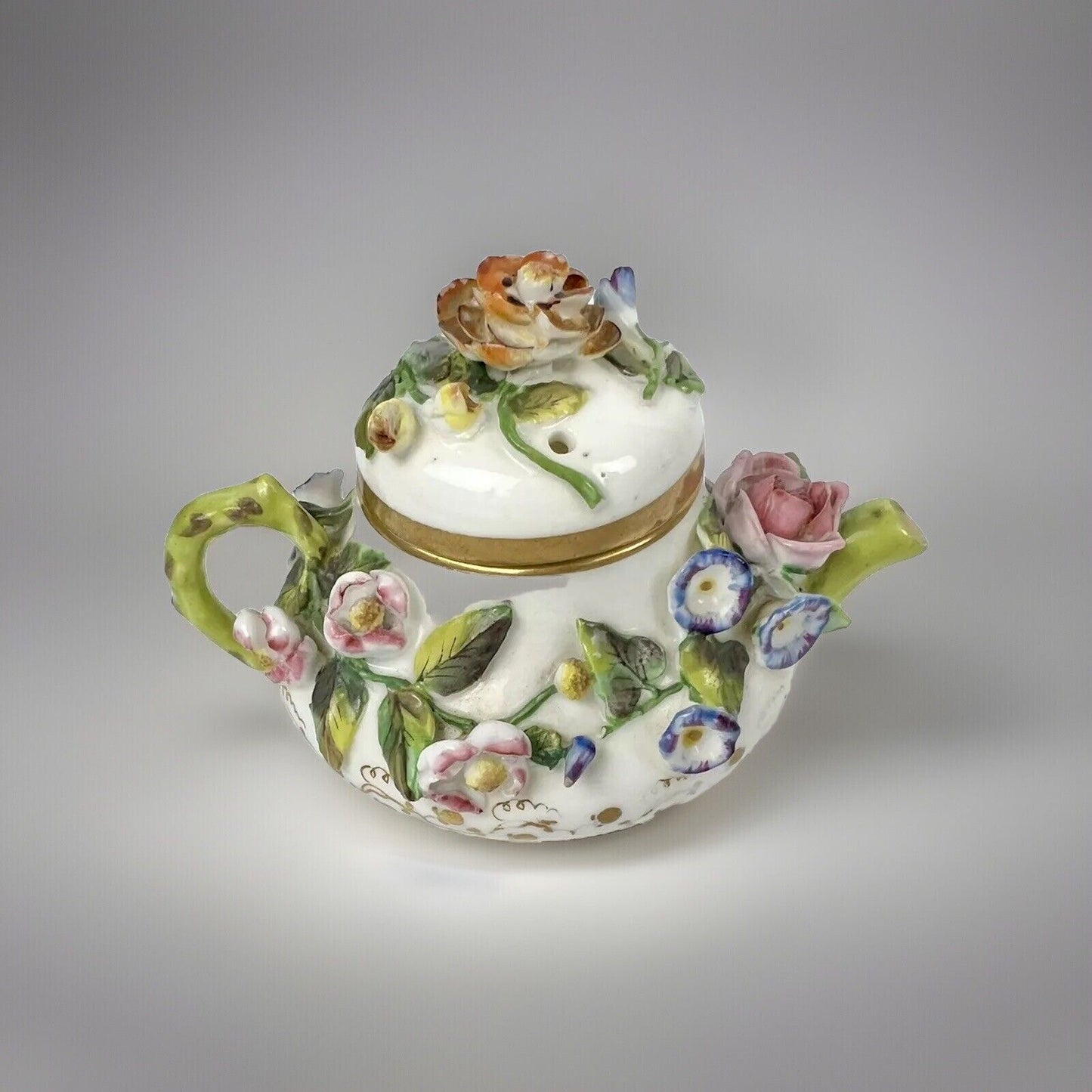 A Rockingham flower-encrusted squat globular teapot and cover. Puce mark 1831-7