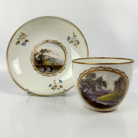 A Pinxton cup and saucer in pattern 174 with painted scenes by Billingsley c1810