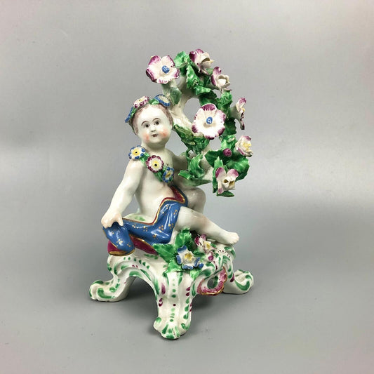 A pair of Bow putti with rococo C-scroll bases and bocage c.1760