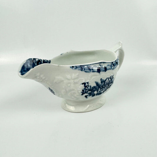 A Lowestoft small sauceboat c1775 with moulded panels and printed decoration.