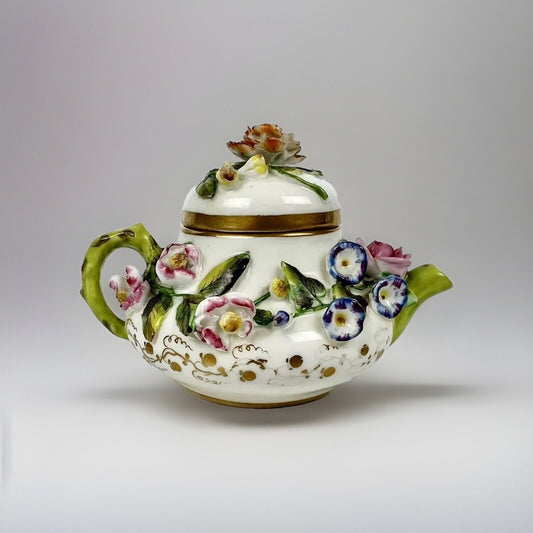 A Rockingham flower-encrusted squat globular teapot and cover. Puce mark 1831-7