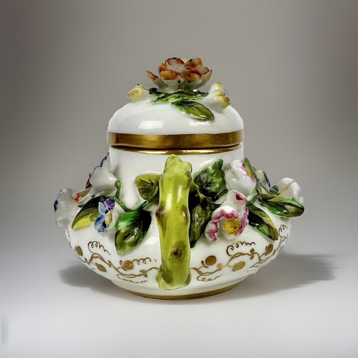 A Rockingham flower-encrusted squat globular teapot and cover. Puce mark 1831-7