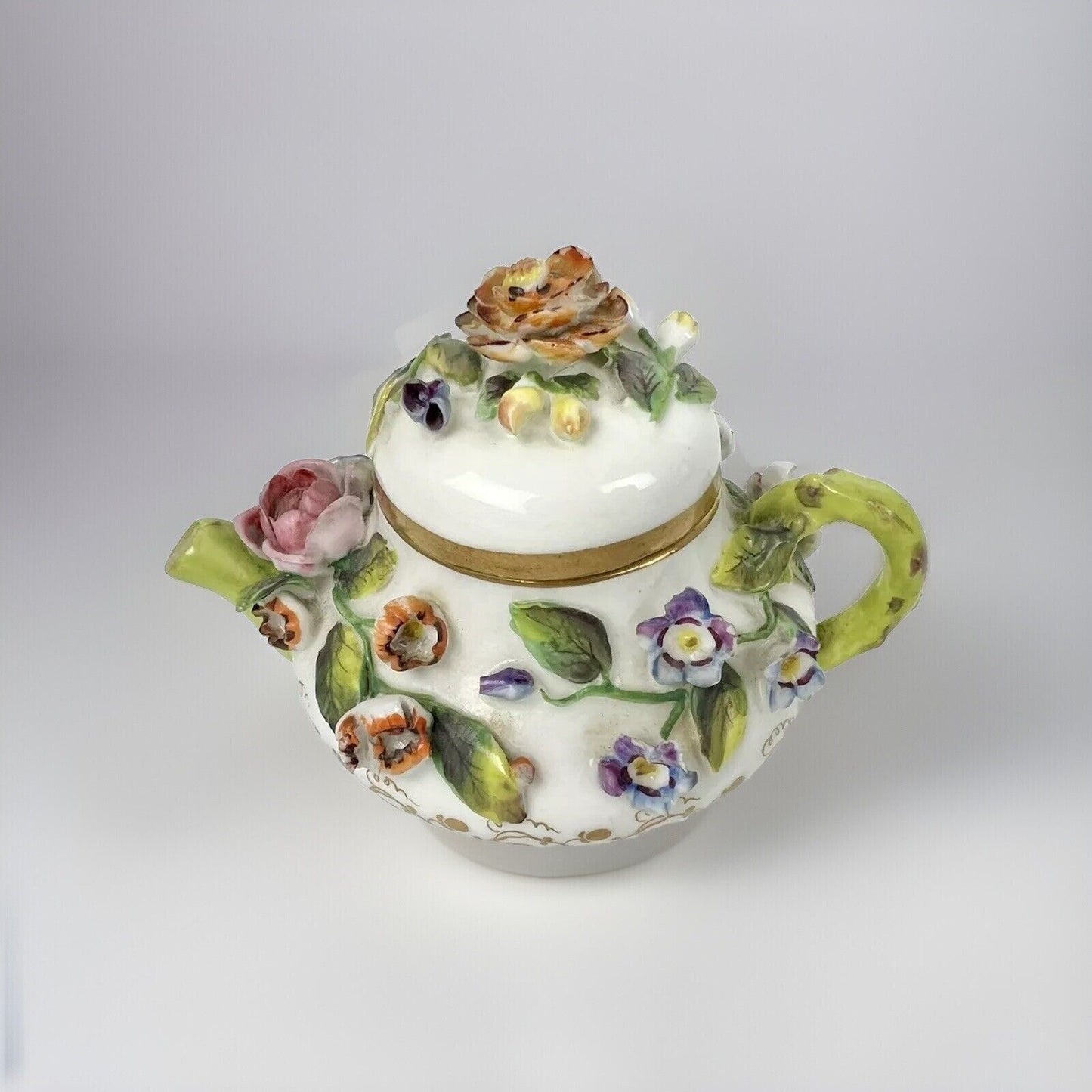 A Rockingham flower-encrusted squat globular teapot and cover. Puce mark 1831-7