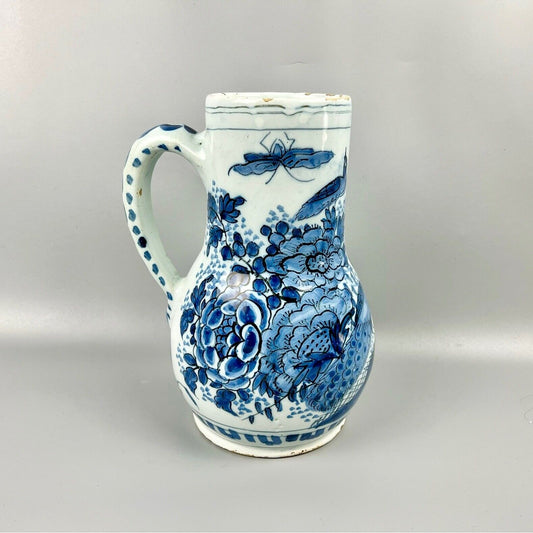An early 18thc Dutch Delft jug painted with peacocks, holey rocks and peonies